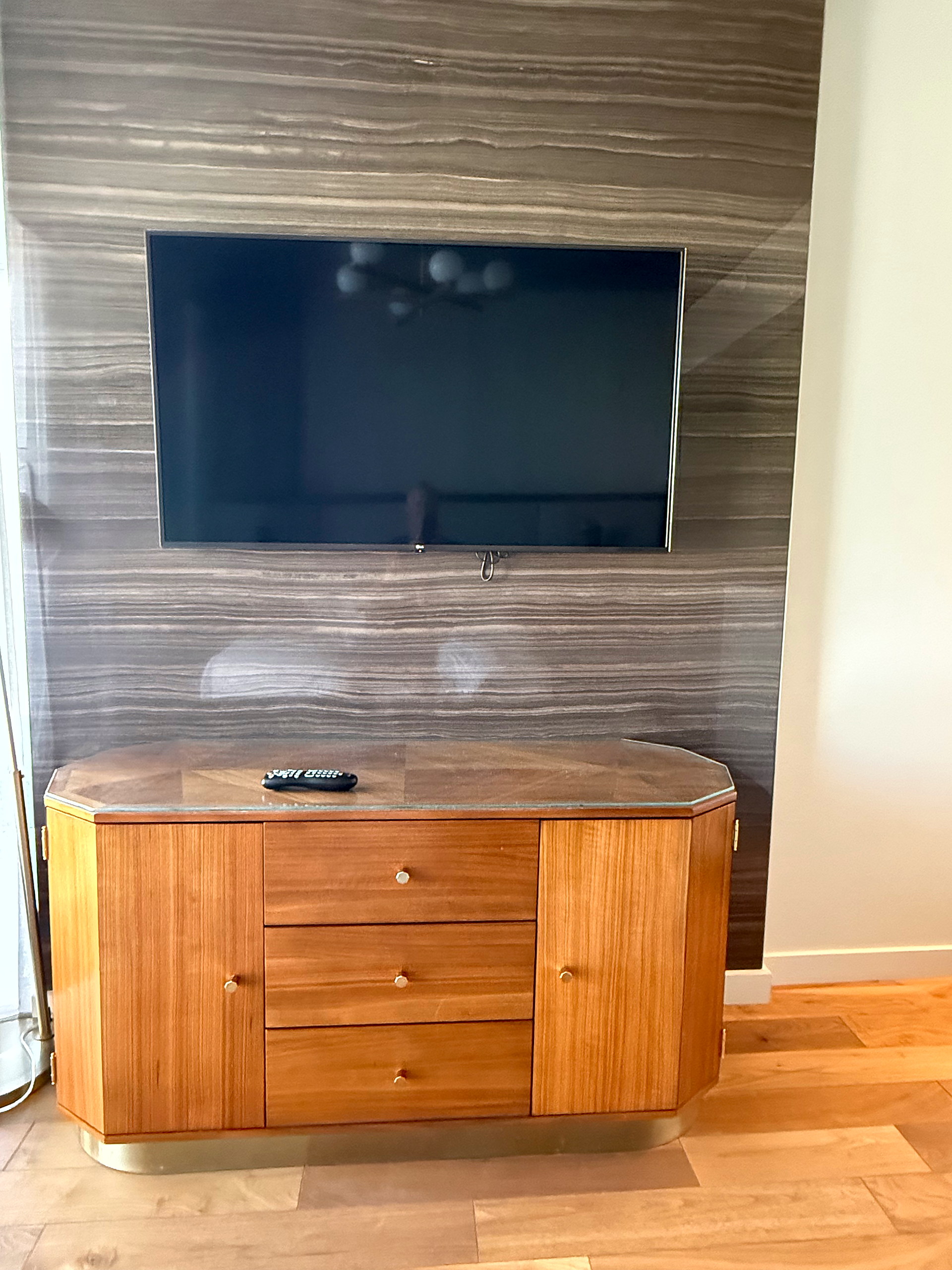 Curved walnut credenza with brass plinth and wall-mounted television