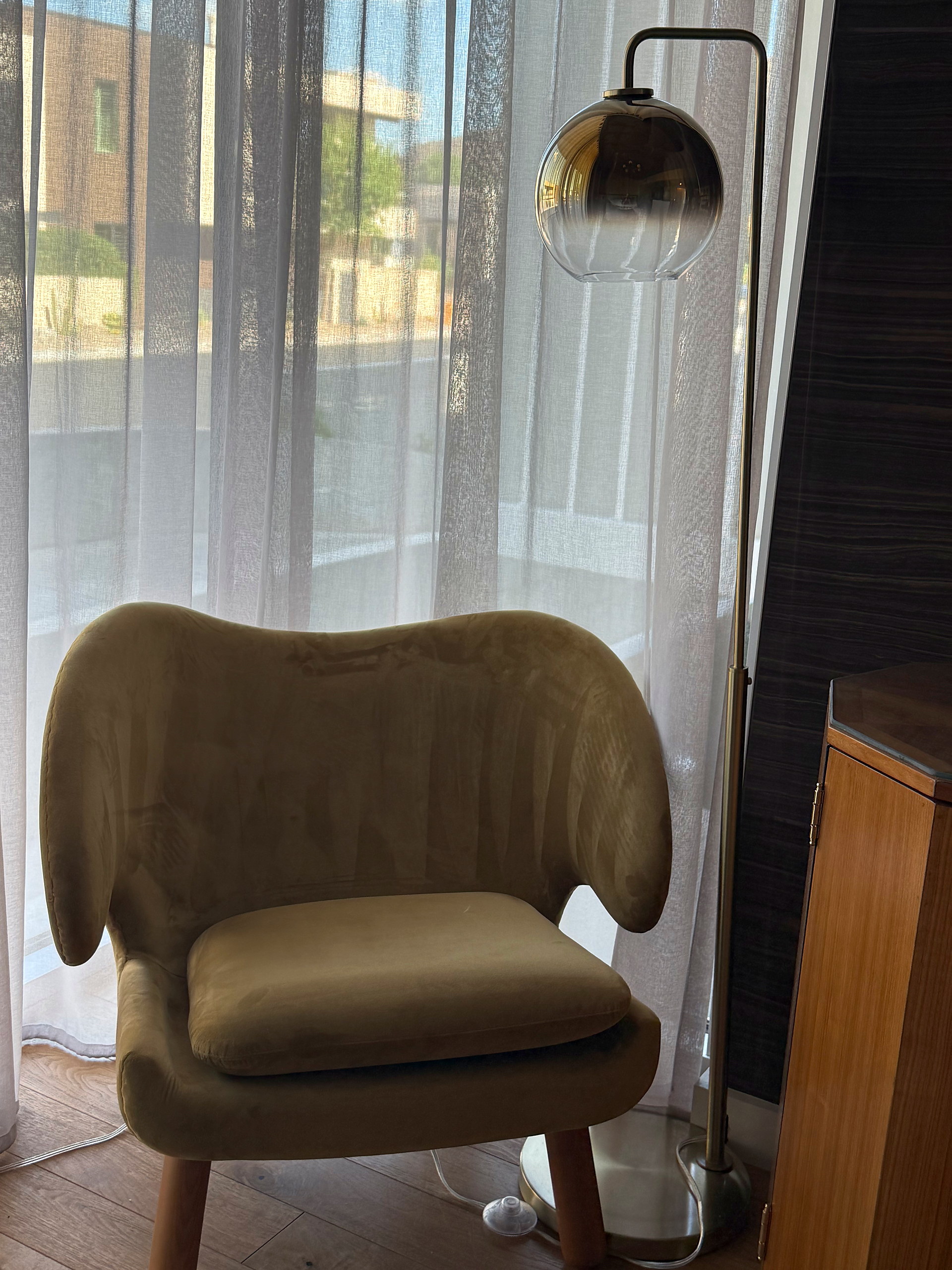 Wing chair against sheer curtains