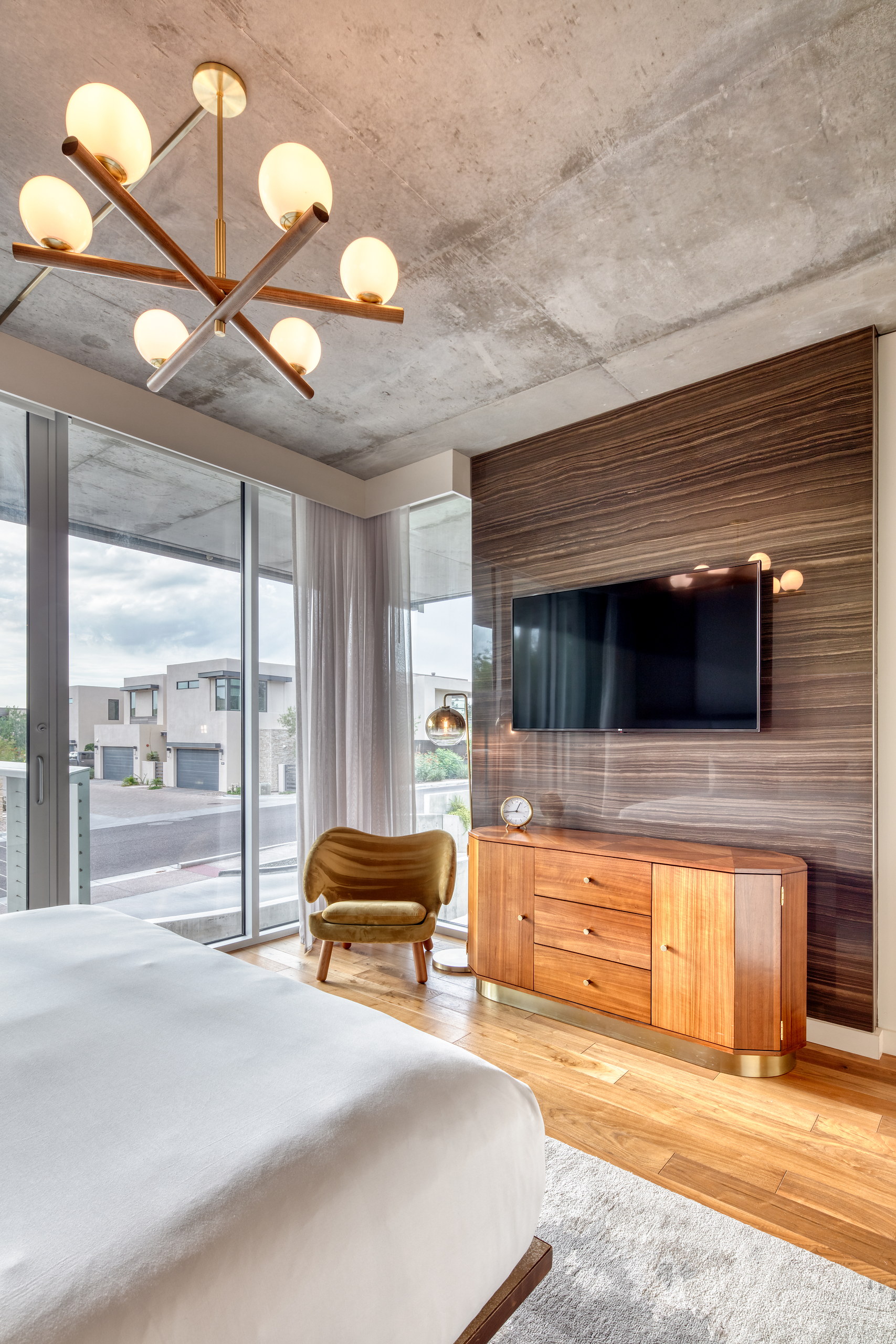Primary bedroom with credenza, television and chandelier