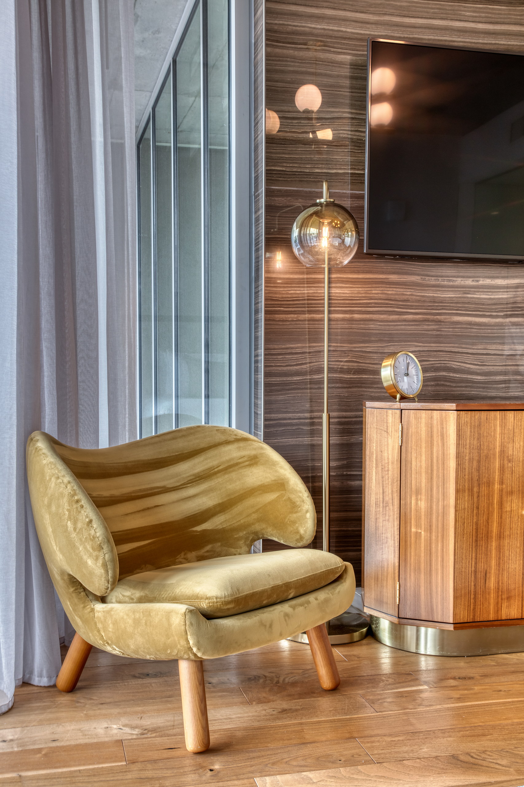 Velvet wing lounge chair beside the walnut credenza